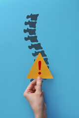 Exclamation mark and spine silhouette. A symbol of pain in the spine