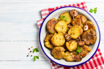 Vegan smashed baked potatoes with garlic sauce on wooden background. Top view, copy space.