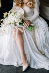Beautiful white bouquet in gorgeous bride's hands. Wedding bouquet with ranunculus and callas