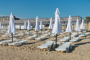 Beautiful empty beach with sun umbrellas and sunbeds. Perfect summer vacation destination. Straw...