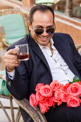 A man in a cafe drinks tea and laughs