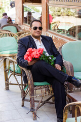 a man with roses sits in a cafe