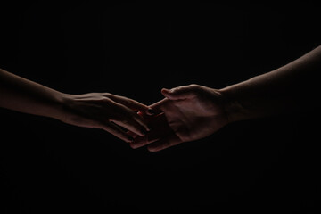 Two hands reaching toward. Helping hand outstretched for salvation on isolated black background....