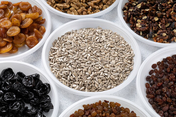 Various dried fruits, nuts and sunflower seeds lie on round plates on a light background. The concept of a healthy healthy diet. Source of vitamins, vegetable proteins and fats, oils.