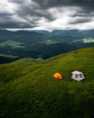 Camping in the mountains with tent standing on a hill, night and sunset landscape