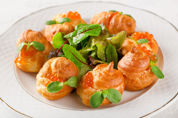 Cold snacks. Buns with curd cheese and red caviar in a white plate on a festive table.