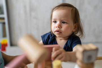 One girl toddler female child playing alone at home with wooden creative educational toys copy space
