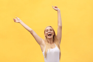 Young beautiful happy girl with hand in the air portrait isolated on yellow background.