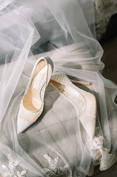 Stylish luxury shoes with lace floral pattern . Modern wedding shoes on tulle in soft morning light. Bridal morning preparations and boudoir. Flat lay