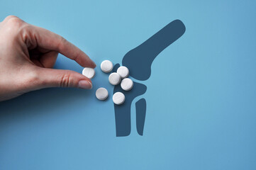 A lot of pills on the silhouette of the joint. A symbol of the treatment of joint disease