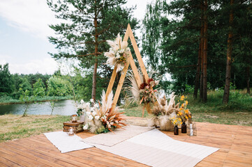 Wedding boho arch decorated with flowers for ceremony against the forrest landscape. wedding ceremony in boho rustic style