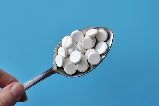 A lot of pills in a spoon. A symbol of uncontrolled self-medication with pills