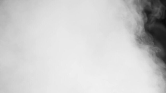 Thick Smoke Slowly Dissipates. The intensity of a white smoke screen on a black background slowly decreases