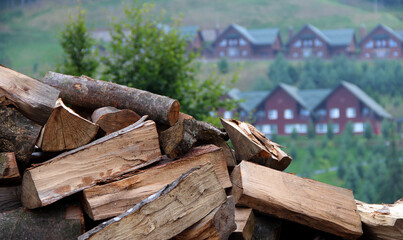 Pile Of Firewood With Wooden Cottages In Background  