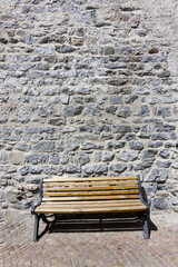 Vecchia panchina di legno accostata ad un muro in pietre antico
