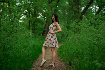 beautiful fashionable brunette girl posing in the park in dress