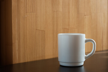 Fototapeta na wymiar White mug for tea and coffee in on a wooden table, close-up