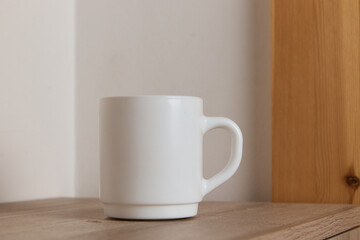 Fototapeta na wymiar White mug for tea and coffee in on a wooden table, close-up