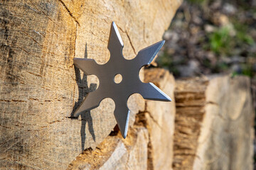 Shuriken (throwing star), traditional japanese ninja cold weapon stuck in wooden background © Sergii