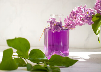 Lilac extract in a glass bottle on a light background