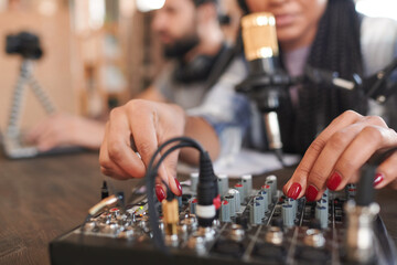 Horizontal close-up shot of modern female blogger adjusting sound settings while her friend...