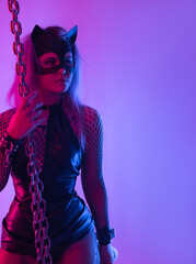 Sexy girl in latex dress bdsm mistress and cat mask in neon light with chains for sex game