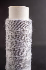 detalle de un carrete de hilo de algodón color gris sobre fondo obscuro