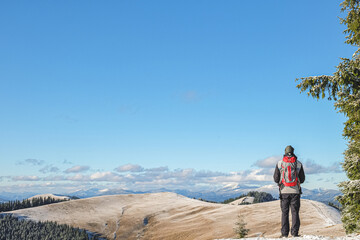 The guy looks at the mountain landscape, hiking in the winter mountains