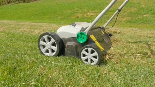 CLOSE UP: Grass aeration for soil compaction relief and grass growth enhancement. Spring backyard garden work for healthier and thicker lawn. Useful gardening machinery for efficiency at landscaping.