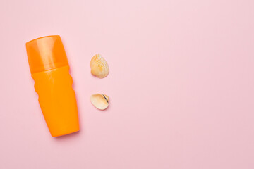 Bottle with sun protection cream and sea shells on color background, top view