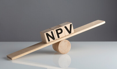 NPV on wooden cubes on a wooden balance , business concept