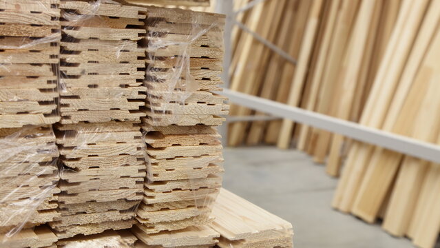Pine wooden lining stack on wooden boards background in stock warehouse.  Profiled boards production. Wood working