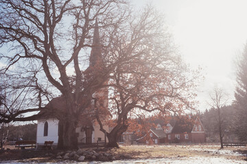 Alte Holzkirche im Harz mit großen Baum im Vordergrund und starker Sonnenschein