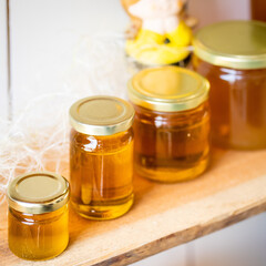 Natural honey in various jars on a wooden shelf, souvenir village market.