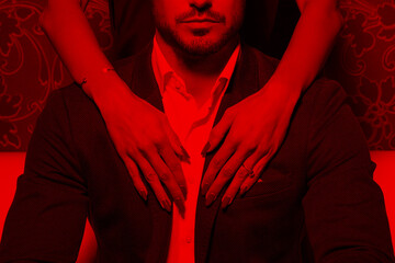 Sexy woman hands embrace rich man in red light - 506137112