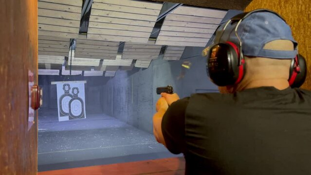 Faceless man shoots at a paper target in the man shape in shooting range