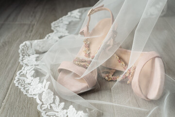 Close-up of elegant shoes under the bride veil. Fashion and wedding day concept.