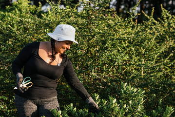 Latina woman gardener outdoors working in a plant nursery with a big smile on her face 