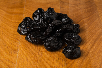 Dried dried prunes in a heap on a wooden board