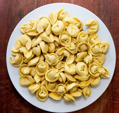 Traditional Italian tortellini (capeletti, agnolini) fresh pasta stuffed with chicken, special for preparing soup on cold nights. Top view