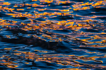 Fototapeta na wymiar Reflection of orange and deep blue color of river ripple waves