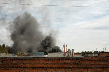 Fototapeta na wymiar Fire in street. Black smoke against sky. Ignition in garage block.