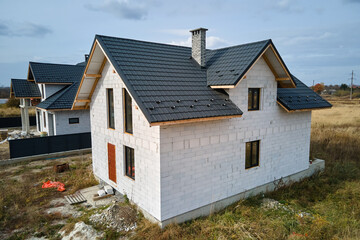 Fototapeta na wymiar Aerial view of unfinished house with aerated lightweight concrete walls and wooden roof frame covered with metallic tiles under construction