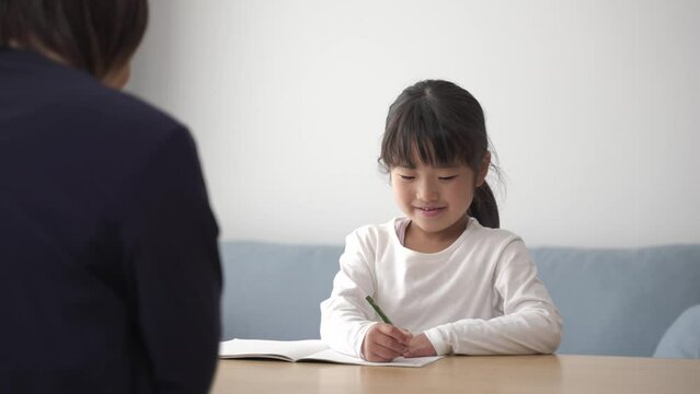 家で勉強をする女の子と見守るお母さん