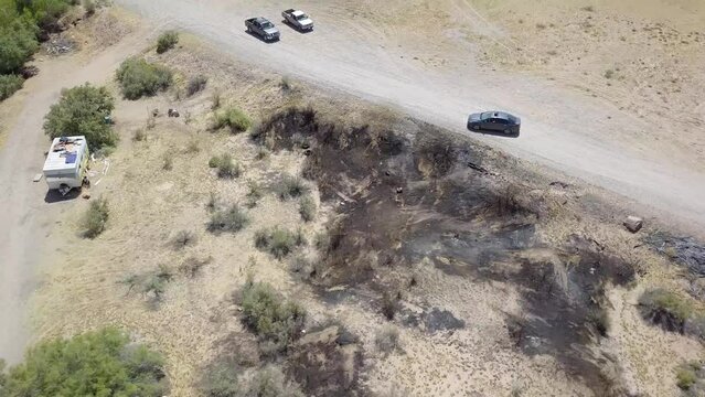 aerial footage of dry brush and dirt with cars and van and lush green palm trees and plants along the Colorado river at Quechan Park in Blythe California USA