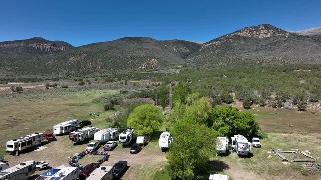 Aerial recreation vehicle camp rural farm 2. Friends and family in rural farm field in mountain valley to camp. Travel club with Motorhomes, trailer and recreation vehicles in nature. Aerial view.