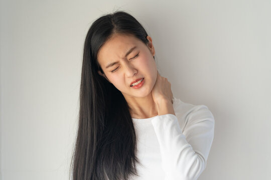 Symptom from Office syndrome, Asian young female rubbing her neck and feeling stiff pain isolated on background.