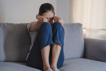 Asian woman covering her face feeling sorrow and depressed sit in the dark bedroom