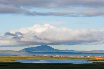 Summer Arctic landscape. Environs of the northern settlement of Ugolnye Kopi. View of the lake, colorful buildings in the tundra, Anadyr estuary and Dionysius Mount. Chukotka, Far East of Russia.
