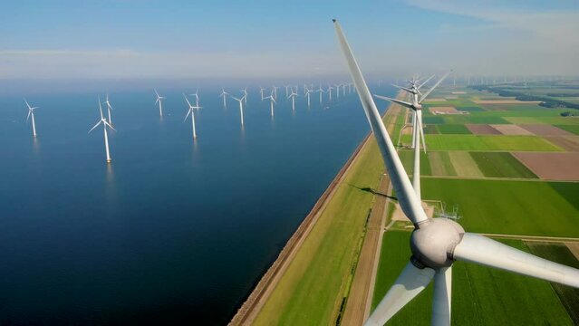 Windmill park in the ocean, drone aerial view of windmill turbines generating green energy electric, windmills isolated at sea in the Netherlands. High quality 4k footage